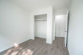 Edmonton apartment for rent - a bedroom with white walls and wood flooring and a closet