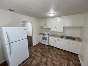 Dallas house for rent - an empty kitchen with white appliances and white cabinets