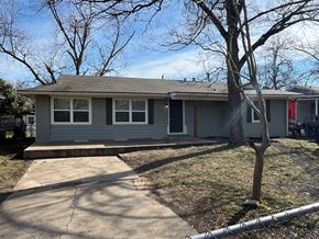 Dallas house for rent - A grey house with a red door and a tree in front.