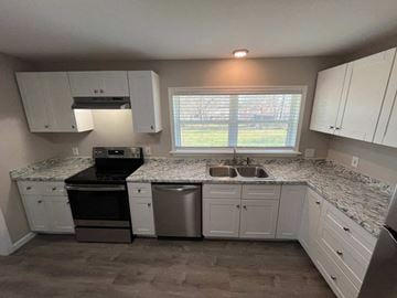 Dallas house for rent - A kitchen with white cabinets and a marble countertop.
