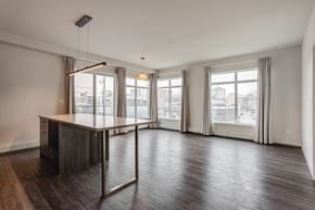 Edmonton apartment for rent - an empty living room with a large window and a table