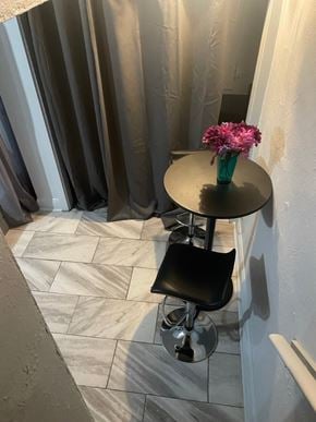 Washington apartment for rent - A black stool is in front of a round table with a vase of pink flowers on it.