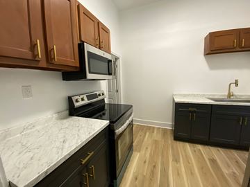 Louisville apartment for rent - A kitchen with black cabinets and a white marble countertop.