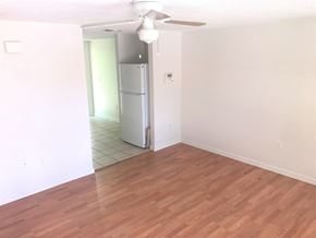 Bradenton house for rent - an empty living room with a hard wood floor and a refrigerator