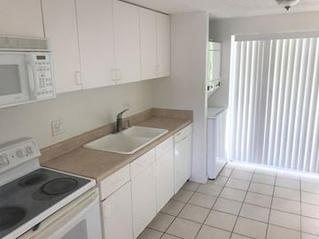 Bradenton house for rent - a kitchen with white cabinets and a sink and a stove