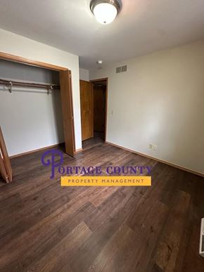 Stevens Point apartment for rent - A room with wood flooring and a Portage County Property Management logo.