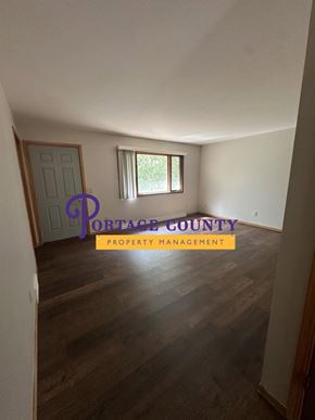 Stevens Point apartment for rent - A room with wooden flooring and a window with a view of greenery outside.