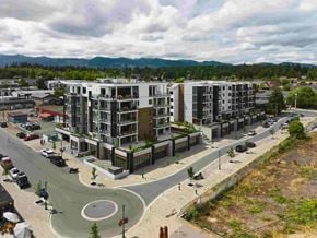 Qualicum Beach apartment for rent - A modern apartment complex with a roundabout in front.