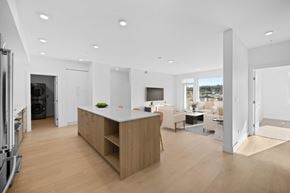 Qualicum Beach apartment for rent - A modern kitchen with a wooden island and a dining area with a table and chairs.