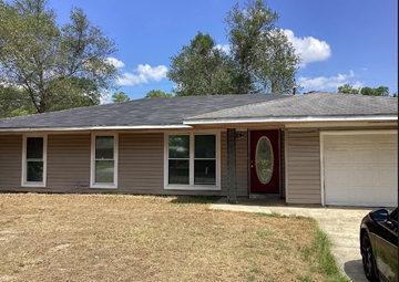 Deridder house for rent - a tan house with a red door and a lawn