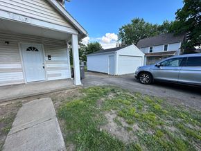 Lima house for rent - A white garage with a door numbered 177 is shown with a silver car parked in front of it.