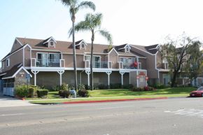 Anaheim apartment for rent - a building with palm trees in front of it on a street