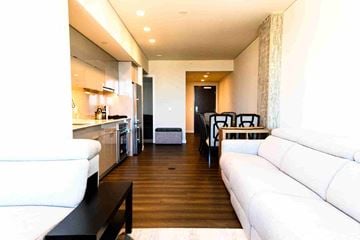 Seattle apartment for rent - A white couch sits in a modern living room with a kitchen area in the background.