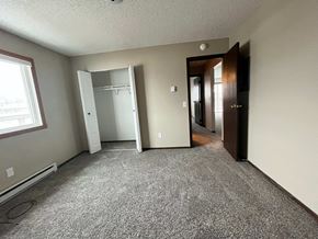 Grand Forks apartment for rent - an empty living room with a carpeted floor and a door to a closet