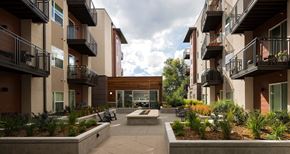 Denver apartment for rent - A courtyard surrounded by apartment buildings with a wooden doorway in the middle.