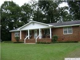 Anniston apartment for rent - a red brick house with a porch and a green lawn
