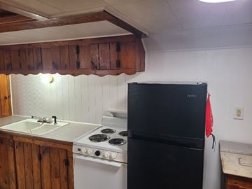 Monmouth apartment for rent - A black fridge and stove in a kitchen with wooden cabinets.