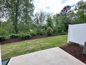 Moore house for rent - a yard with a white fence and grass and trees