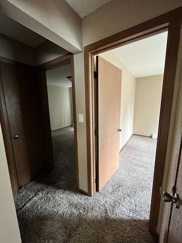 Grand Forks apartment for rent - a bedroom with a door open to a hallway with a carpeted floor