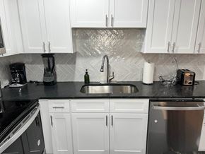 Atlanta apartment for rent - A kitchen with white cabinets and a black countertop.