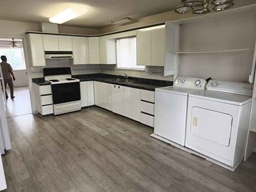 Vancouver apartment for rent - A man is standing in a kitchen with white cabinets and a black countertop.
