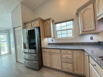 Bradenton house for rent - a kitchen with wooden cabinets and a stainless steel refrigerator