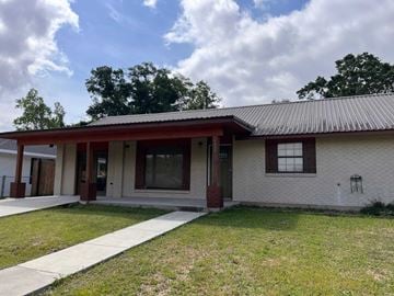 Deridder house for rent - the front of a white brick building with a porch and a sidewalk