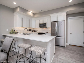 Waukee apartment for rent - A kitchen with white cabinets and a white island with three barstools.