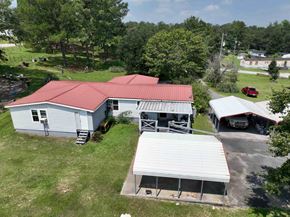 Milledgeville apartment for rent - A house with a red roof and a garage is surrounded by greenery.