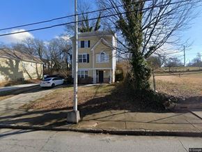 Atlanta apartment for rent - A white car is parked on the street in front of a yellow house.