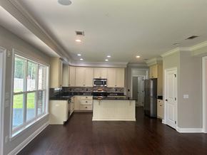 Baker house for rent - a kitchen with white cabinets and black counter tops and a large window