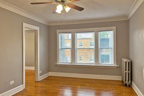 Chicago apartment for rent - A room with a ceiling fan and a window with a view of a building outside.
