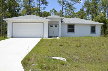 Lehigh Acres house for rent - a white house with a driveway and a garage door