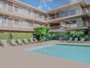 Sherman Oaks apartment for rent - A pool surrounded by lounge chairs and umbrellas in front of a building.