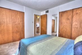 Albuquerque apartment for rent - A bedroom with a bed in the center and wooden walls.