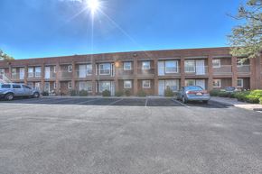 Albuquerque apartment for rent - A sunny day at a parking lot in front of a brick building.