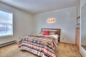 Albuquerque apartment for rent - A bedroom with a bed covered in a colorful comforter.