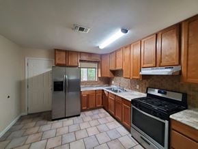 New Llano house for rent - an empty kitchen with stainless steel appliances and wooden cabinets