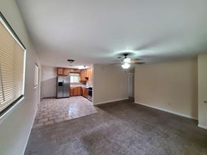 New Llano house for rent - an empty living room with a kitchen in the background