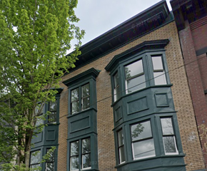 Vancouver apartment for rent - A green building with a tree in front of it.