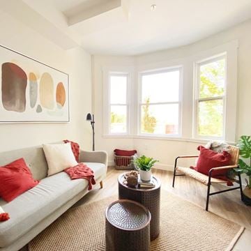 Vancouver apartment for rent - A living room with a grey couch, red pillows, and a painting on the wall.