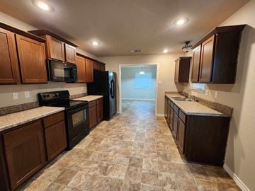 Killeen house for rent - a kitchen with wood cabinets and black appliances