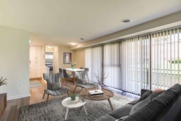 Suitland apartment for rent - A living room with a grey couch, a white coffee table, and a dining table with chairs.