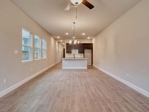 San Antonio apartment for rent - an empty living room with a kitchen and a ceiling fan