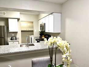 Irving house for rent - a kitchen with white cabinets and a vase with flowers