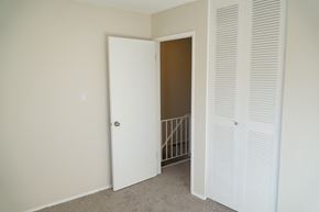 Edmonton apartment for rent - a bedroom with white closet doors and a hallway with a staircase