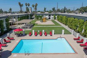 Santa Fe Springs apartment for rent - A pool with a diving board and red chairs.