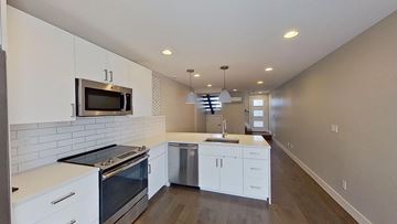 Denver house for rent - a kitchen with white cabinets and a stove and a microwave