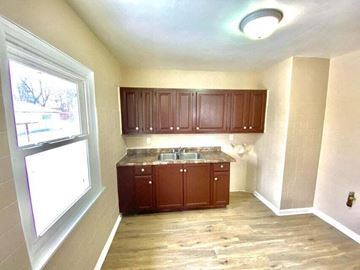 Gary house for rent - a small kitchen with wooden cabinets and a window