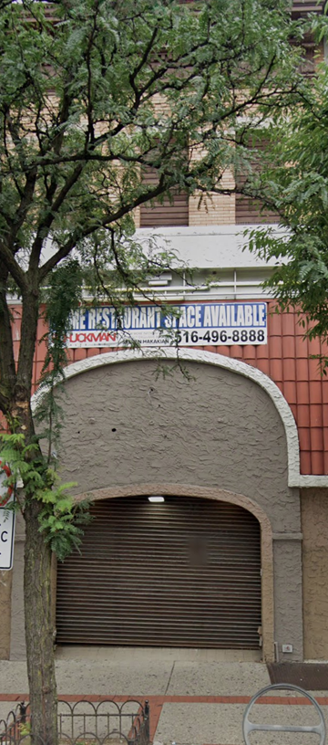 Flushing apartment for rent - a building with a garage door and a tree